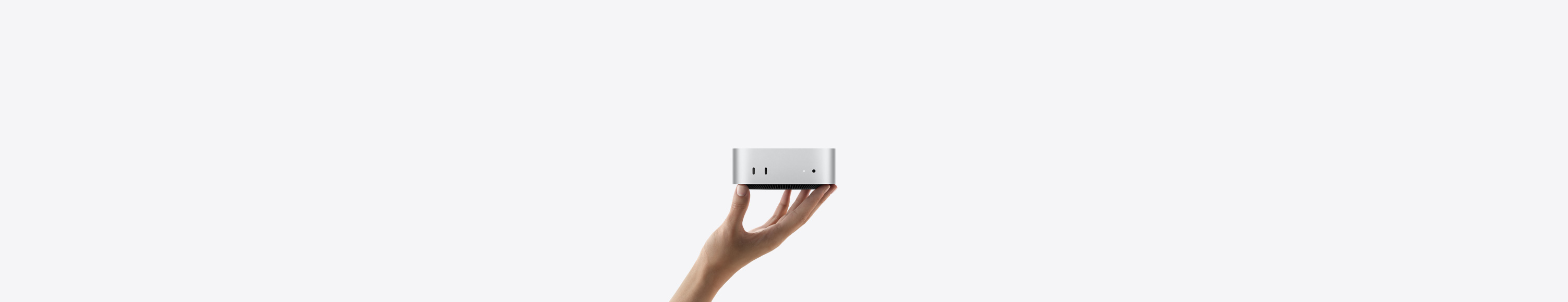 Yukarı doğru açık bir elin parmak uçları üzerinde dengede duran Mac mini’nin önden görünümü, iki adet Thunderbolt bağlantı noktası, durum göstergesi ışığı ve kulaklık jakı, altta konik tasarımlı siyah taban, düz üst yüzey, yuvarlatılmış köşeler, düz kenarlar, gümüş rengi